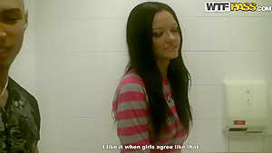 Brunette Aurora gives blowjob to two dicks in public toilet