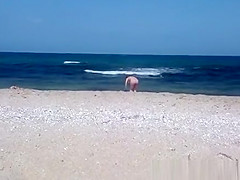 Pregnant nudist woman at beach