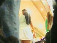 Upskirt video of a brunette in a white dress being pursued by a